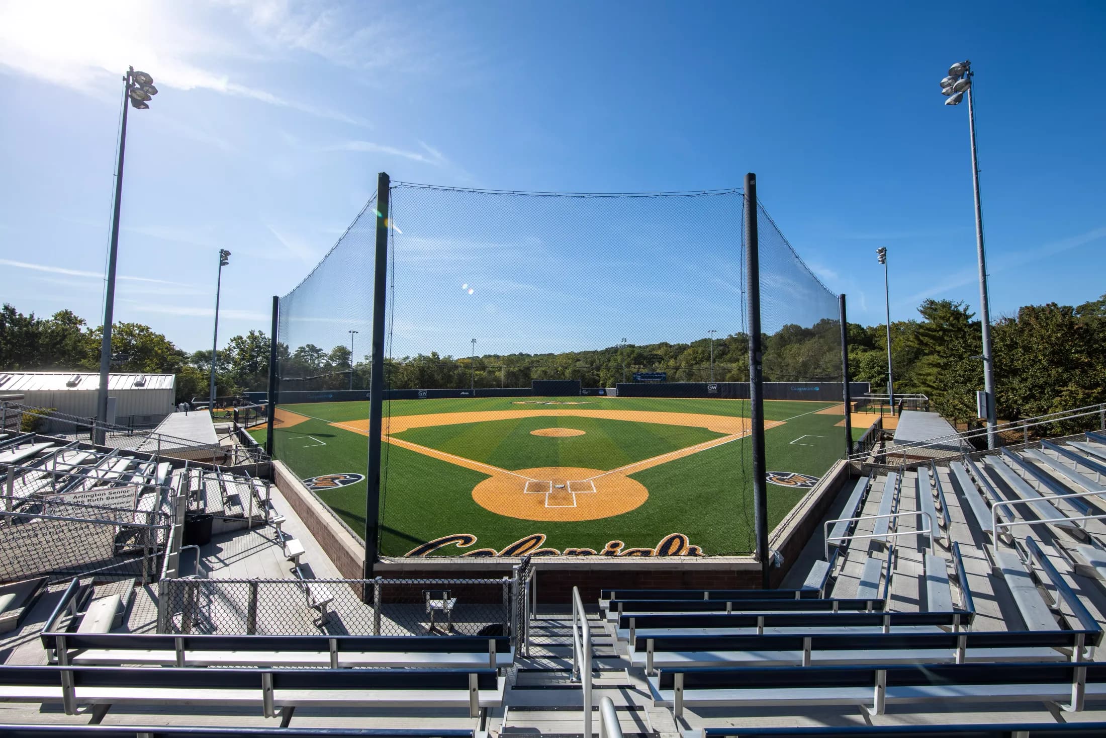 Tucker Field at Barcroft Park’s actual bleachers, protective netting and diamond from the stands in GW’s official collection published in May 2020. This historical view retains the foreground railings and netting, without an exact capture date or numbered camera seat.
