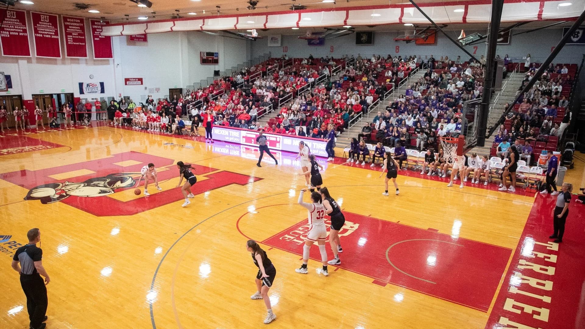 Case Gym during the 2023 Patriot League Women’s Basketball Championship, as identified by Boston University’s official facility collection. The wide elevated sideline view shows the court, red chairbacks, basket structures and roof. This historical photograph does not establish current ticket inventory or an exact spectator seat.