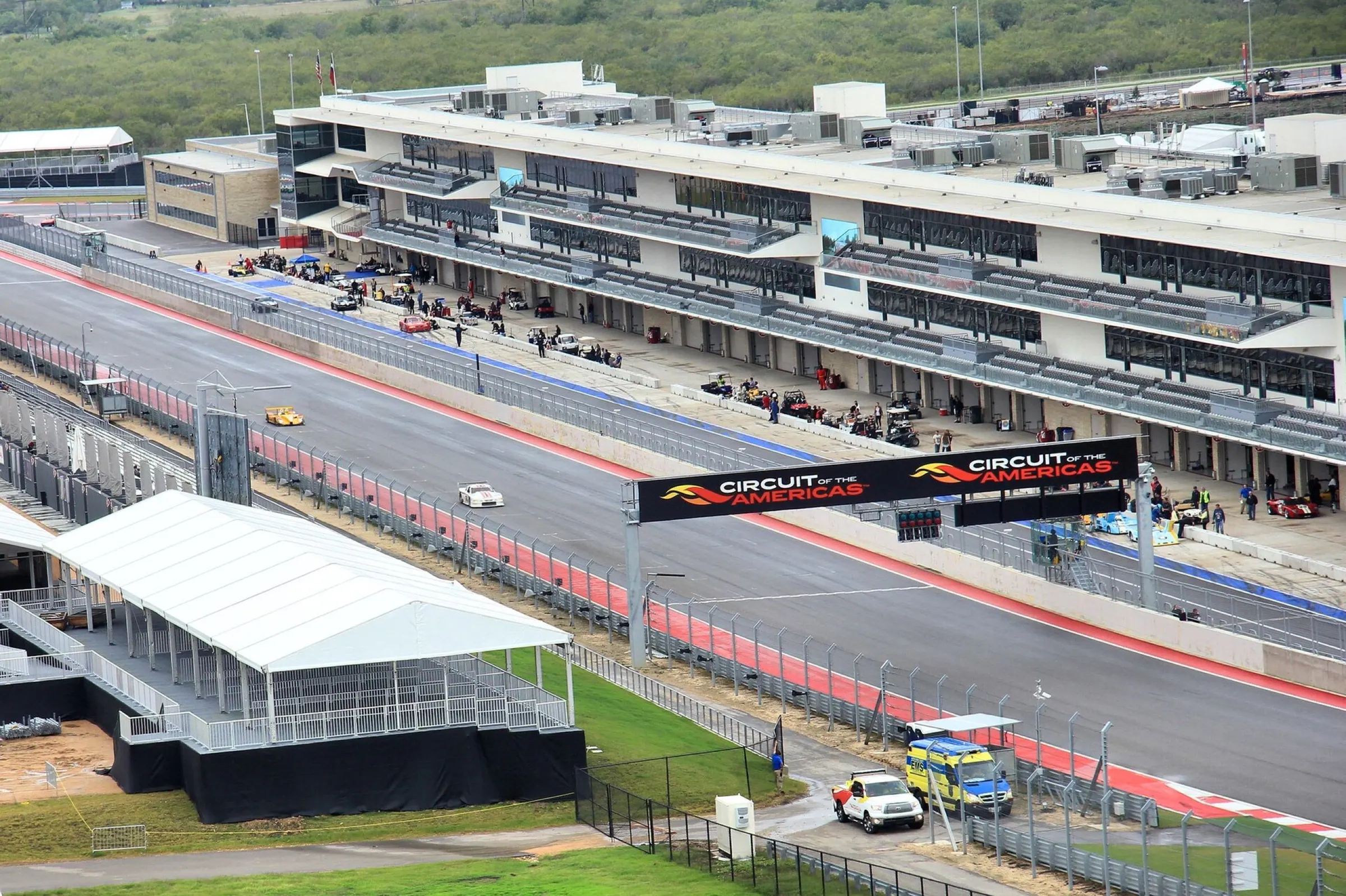 Wide planning view of the Circuit of the Americas pit lane, paddock, and grandstand.