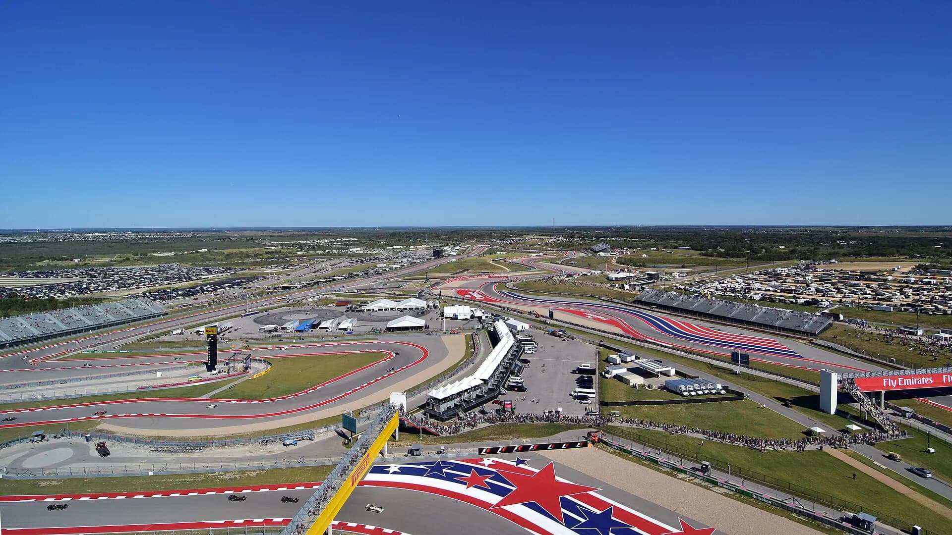 Wide elevated view across Circuit of the Americas showing multiple turns, grandstands, and the scale of the grounds.