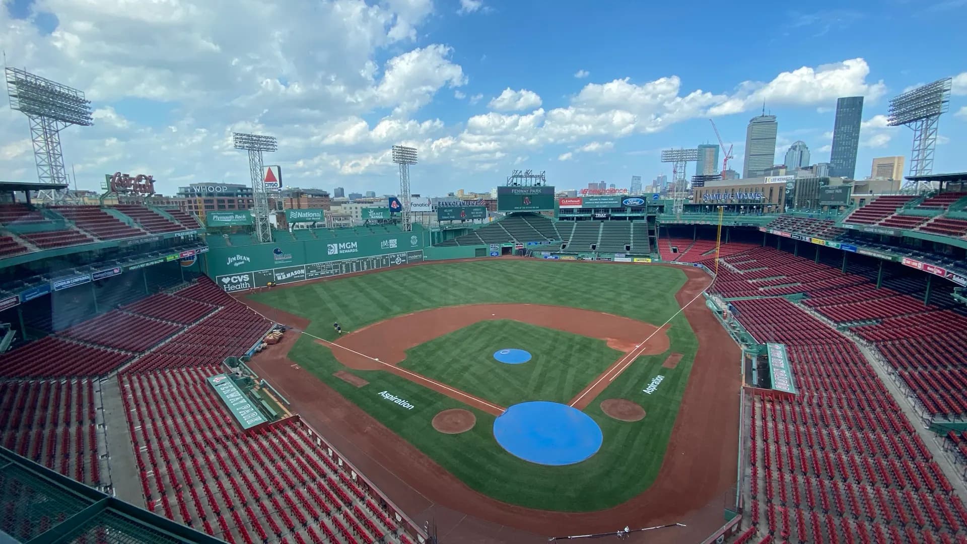 Press-box view across Fenway Park's complete diamond, Green Monster, seating bowl, scoreboards, and Boston skyline.