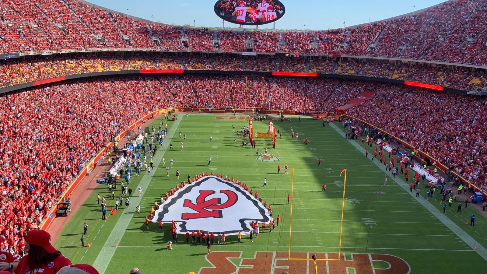 Packed game-day view across GEHA Field at Arrowhead Stadium with the current name on the scoreboard.