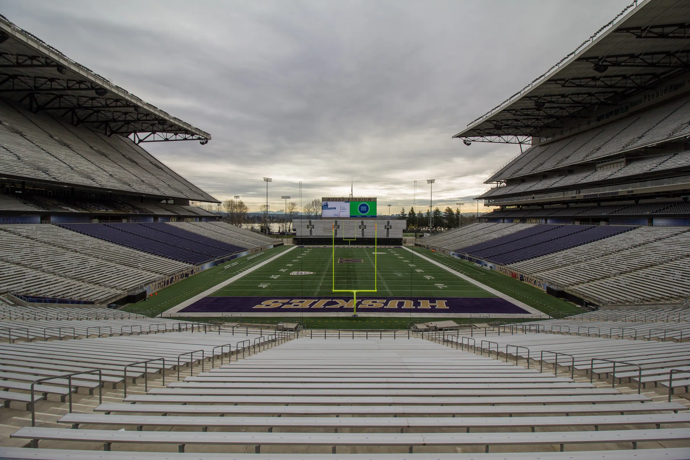 Centered wide view of Husky Stadium's entire field, both covered grandstands, seating bowl, and open waterfront end.