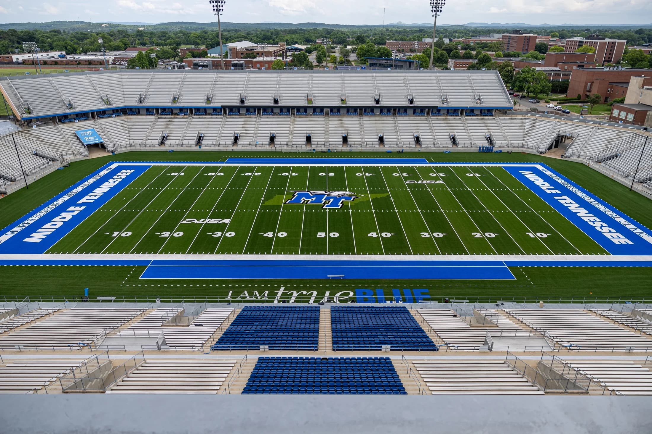 Wide view across Floyd Stadium’s field toward the opposite grandstand, with the lower sideline seats and campus beyond. The owner labels this photograph as the 2025 turf; exact capture date is unstated. Use the current chart and your ticket for section access.