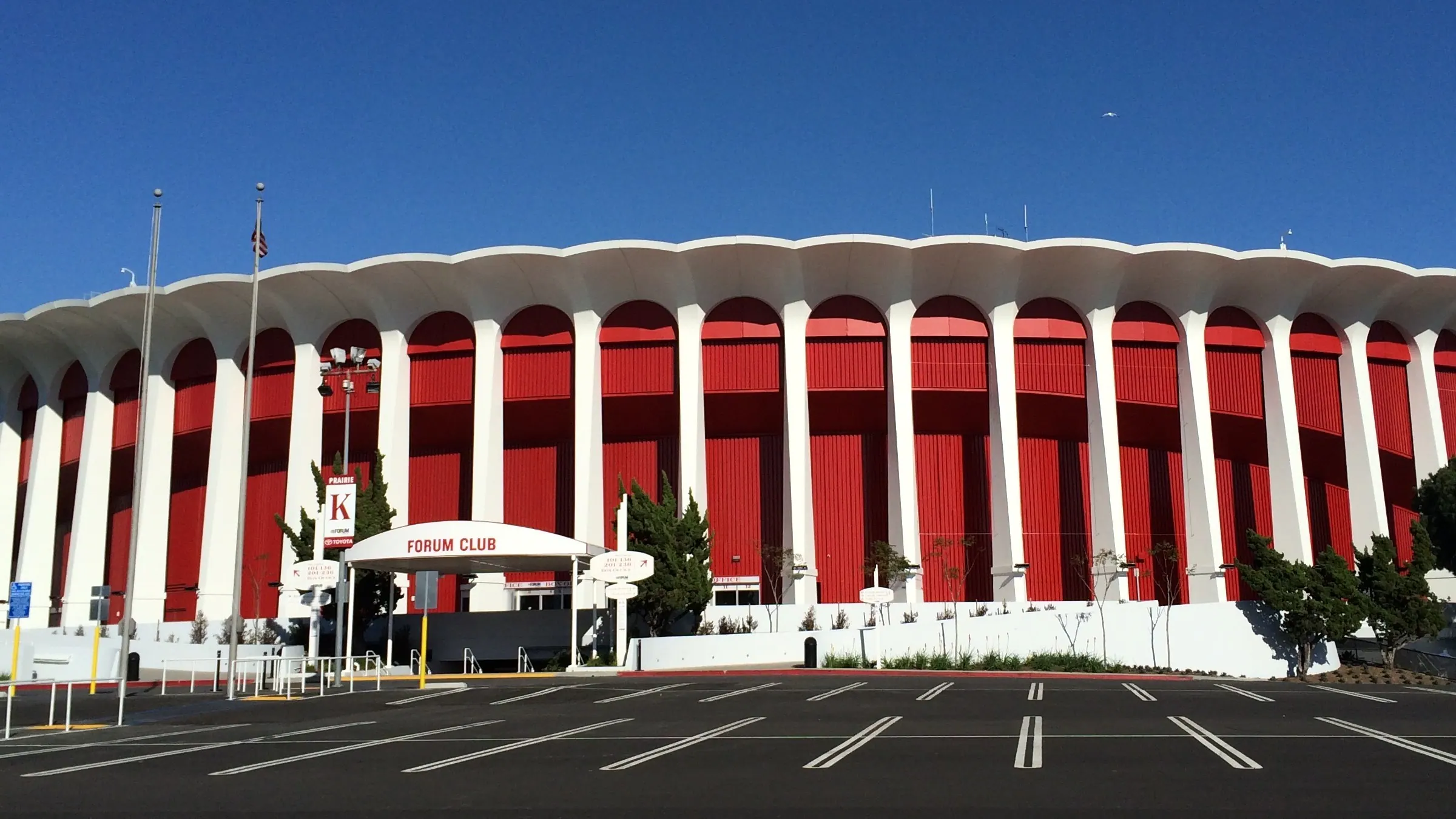 Wide exterior view of the Kia Forum's red-and-white arched facade in Inglewood.