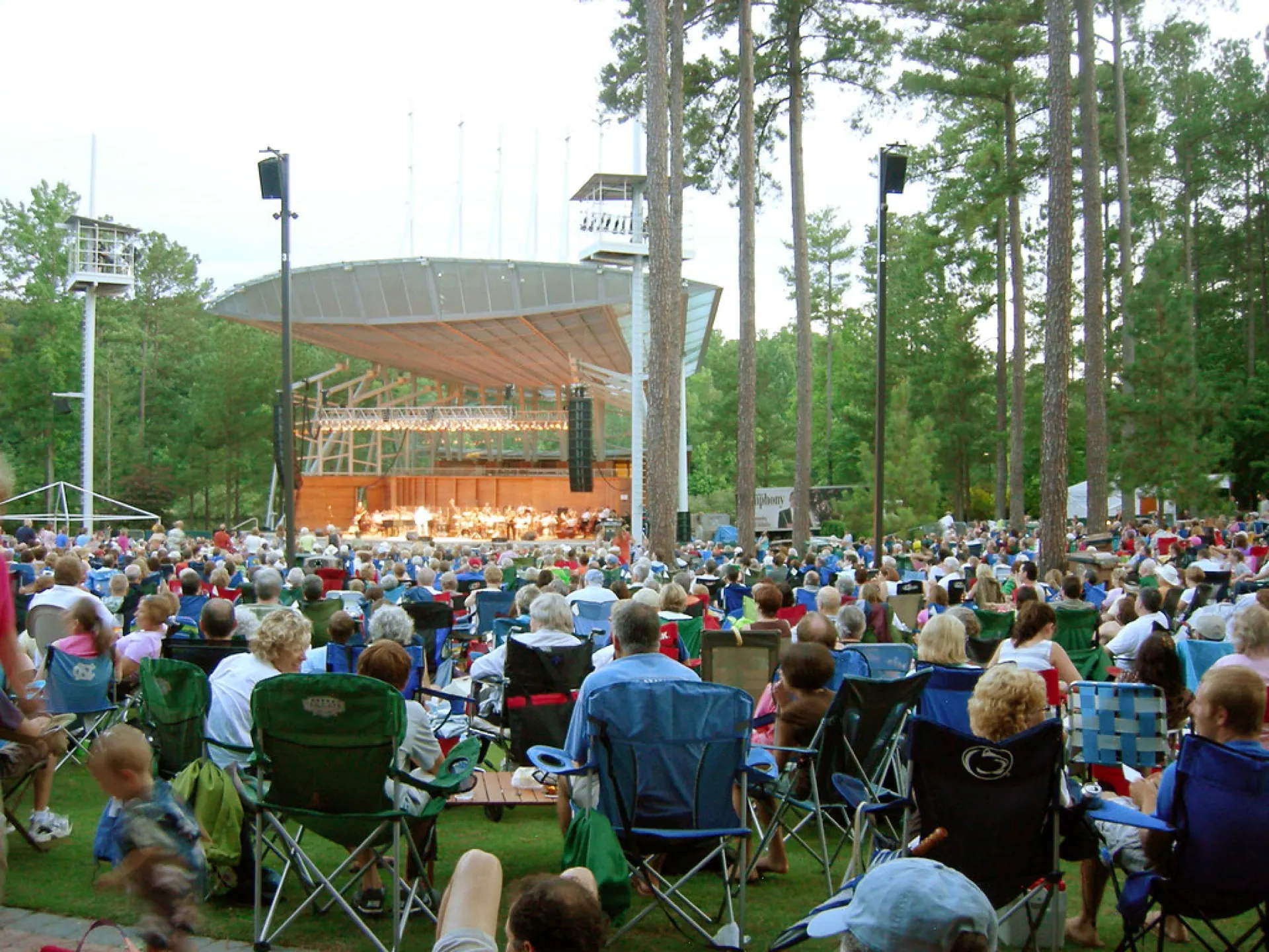 Koka Booth Amphitheatre stage and audience lawn among tall pine trees.