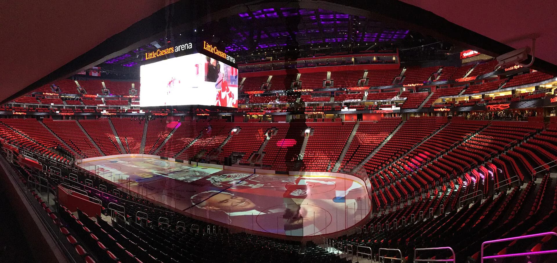 Little Caesars Arena seating bowl and ice rink beneath the center-hung scoreboard.