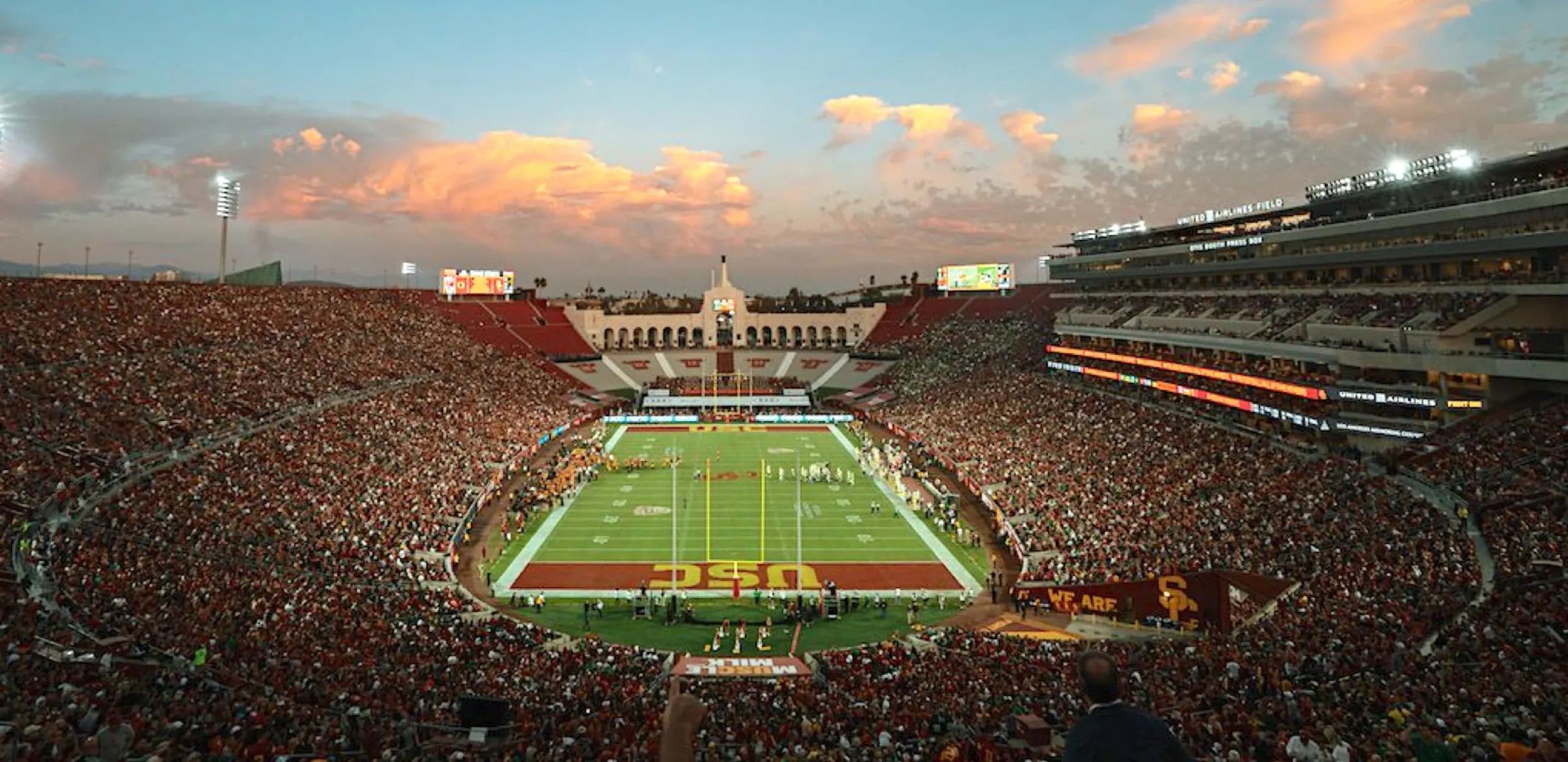 Packed Los Angeles Memorial Coliseum bowl and football field at sunset.
