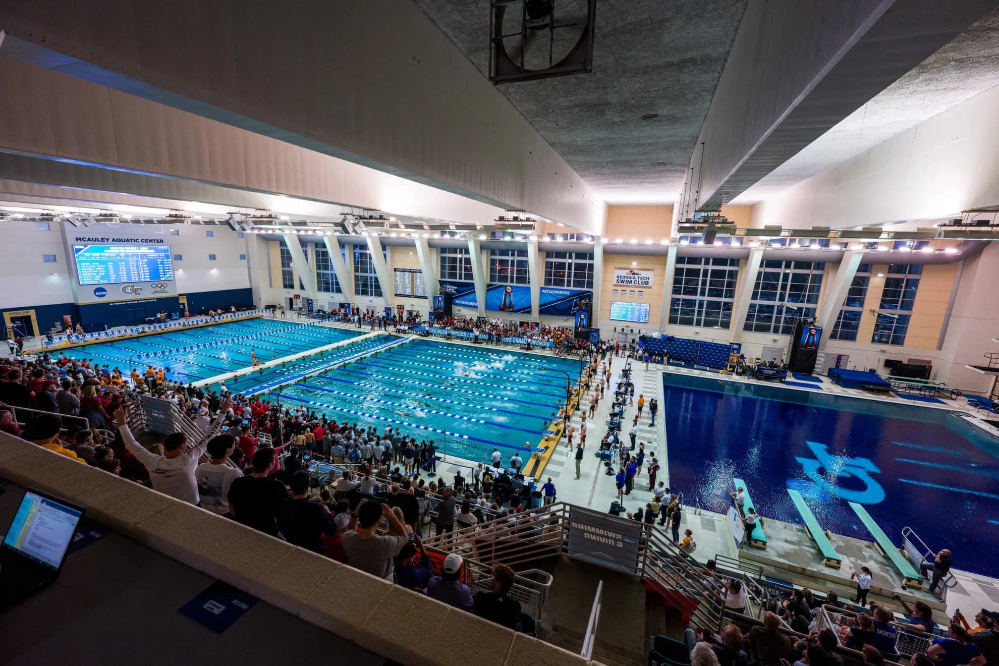 Grandstand view across McAuley Aquatic Center during a swimming meet, photographed by Danny Karnik and published by Georgia Tech Athletics. Match the actual event rather than treating this as an individual-seat view.