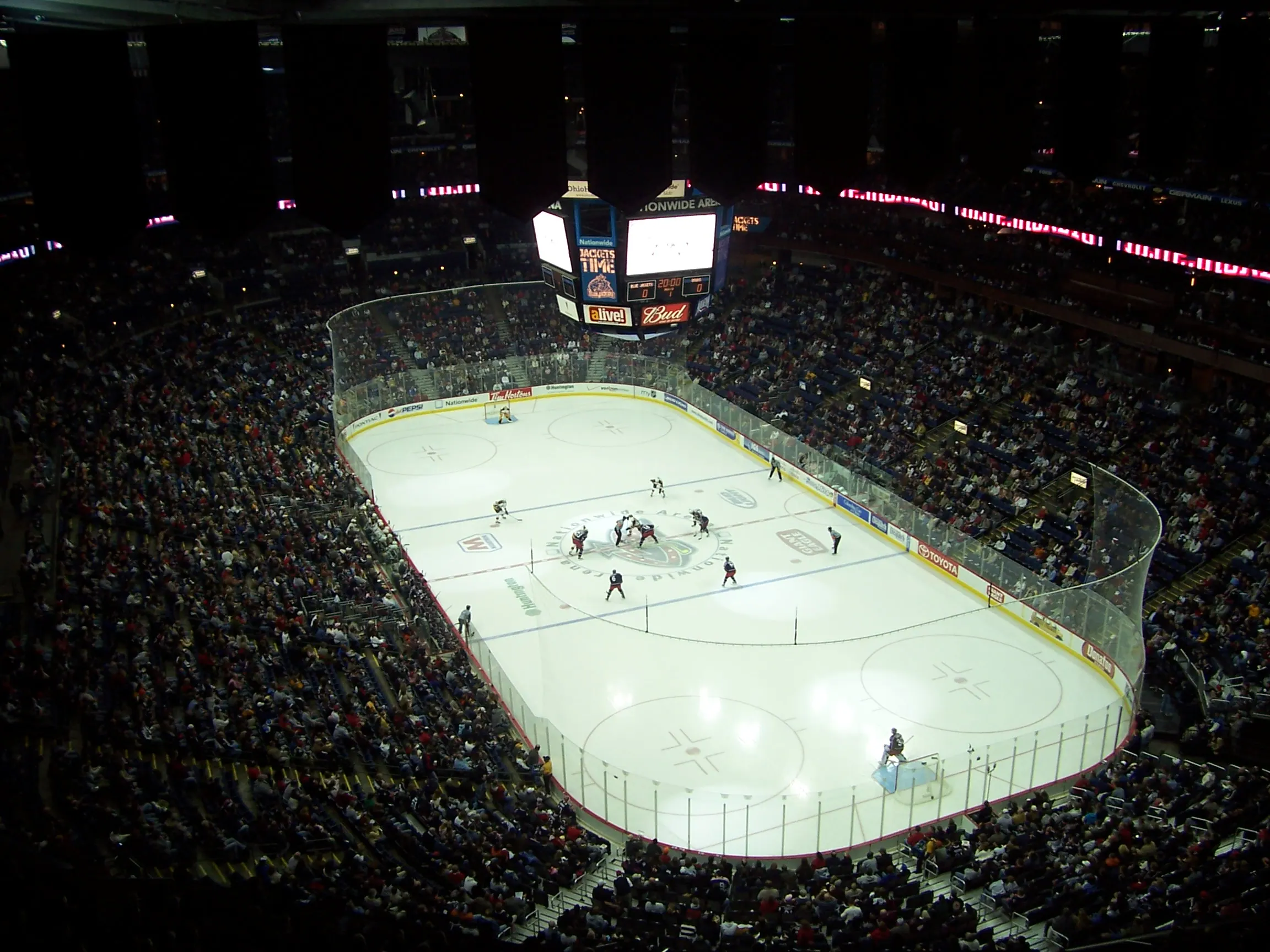 Wide upper-level view of the rink, scoreboard, and seating bowl inside Nationwide Arena during a sold-out hockey game.