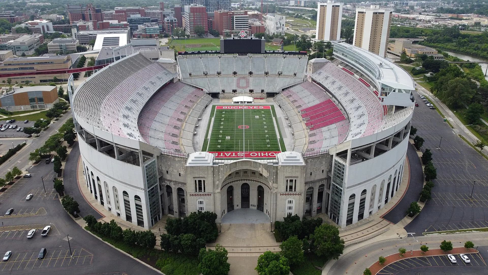 High aerial view of Ohio Stadium's full horseshoe-shaped seating bowl and surrounding Columbus approaches.