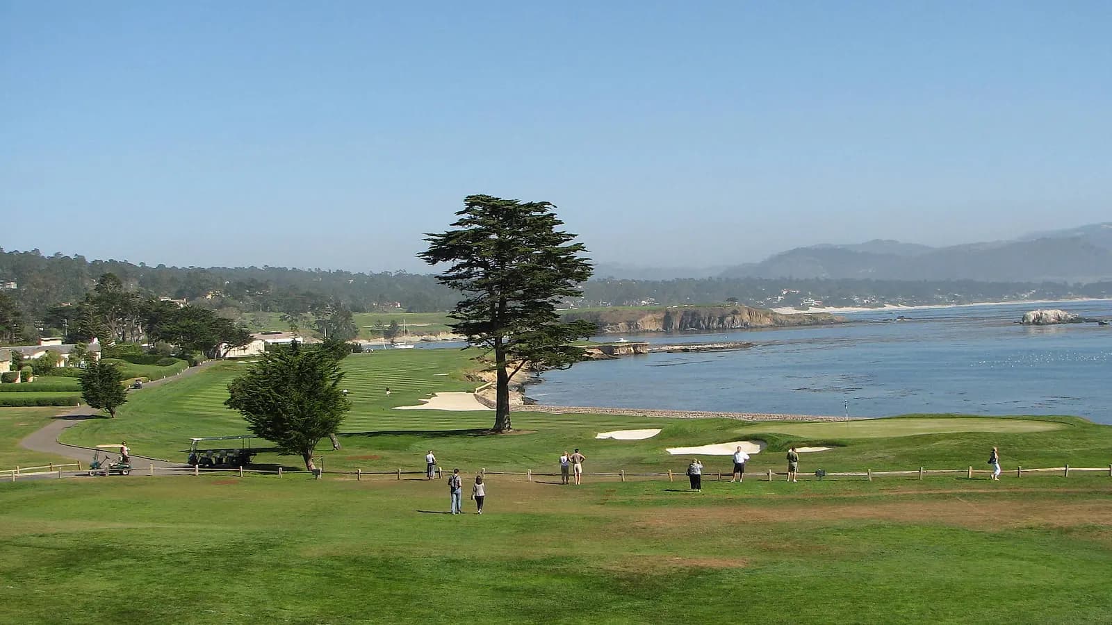 Wide view across Pebble Beach Golf Links' 18th hole and the Pacific coastline.