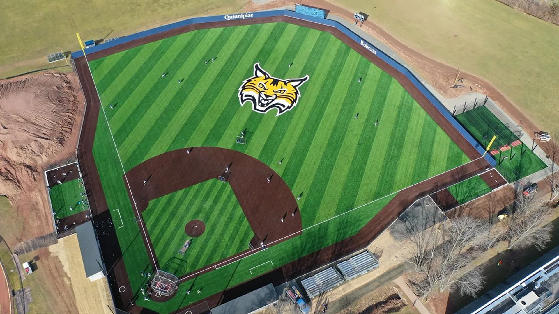 Quinnipiac Baseball Field’s complete striped synthetic diamond in the official aerial explicitly labeled Spring 2024. The view shows the renovated field rather than the old natural-grass layout; it supplies no exact capture day or numbered spectator camera seat.