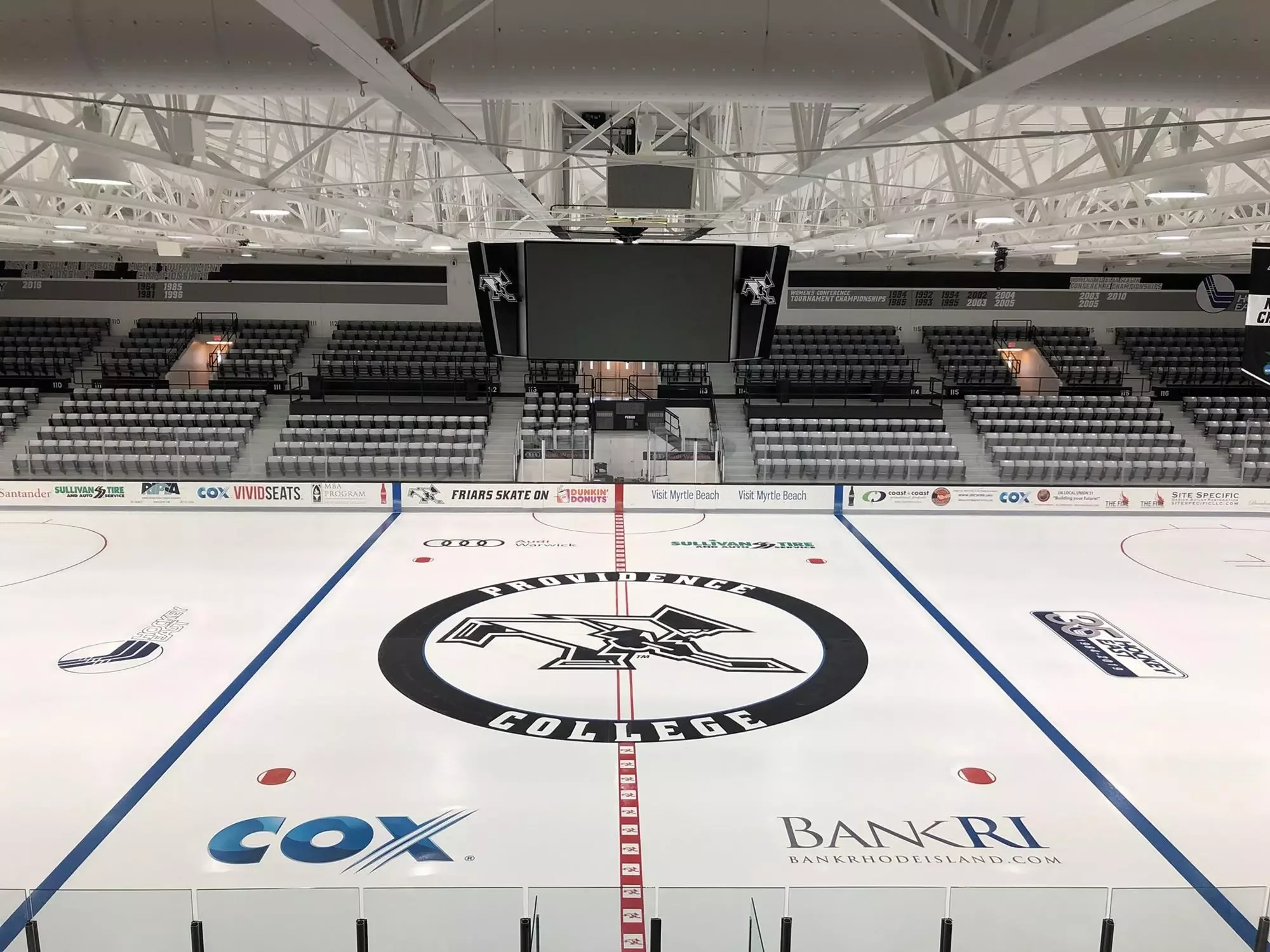 Schneider Arena’s center-ice view across the rink toward numbered seating and the suspended video board, documented in Providence Athletics’ official facility gallery. This older photograph does not establish current advertising or the view from an exact seat.