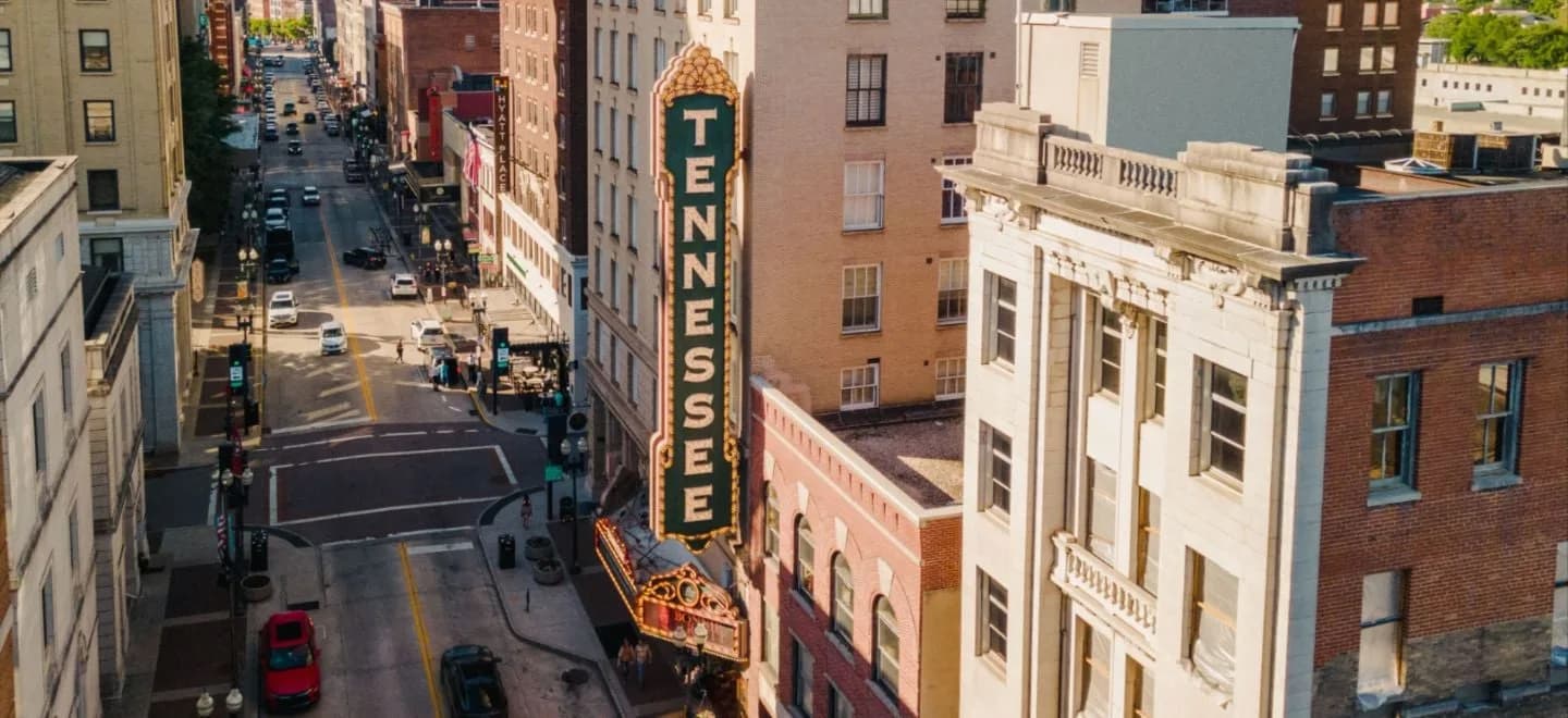 An elevated streetscape view of Tennessee Theatre’s vertical sign and marquee beside the adjacent Gay Street buildings. From the official homepage; this is an arrival-orientation photograph with no stated capture date.