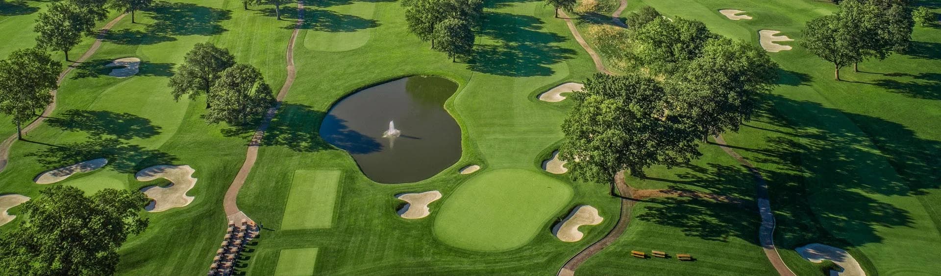 Upper Montclair Country Club — aerial view of course greens, bunkers, a pond and paths from the official tour page. The header photograph does not name a nine or hole, or supply a capture date.