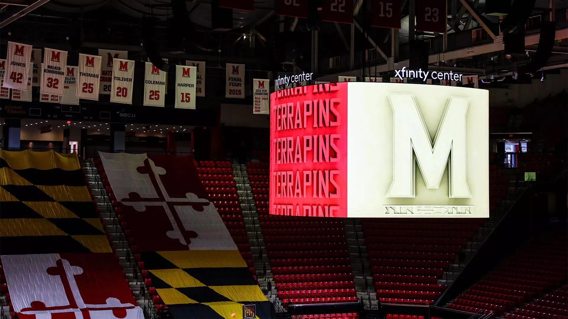 Wide interior view of the XFINITY Center basketball court, Maryland seating, banners, and 2024 center scoreboard.
